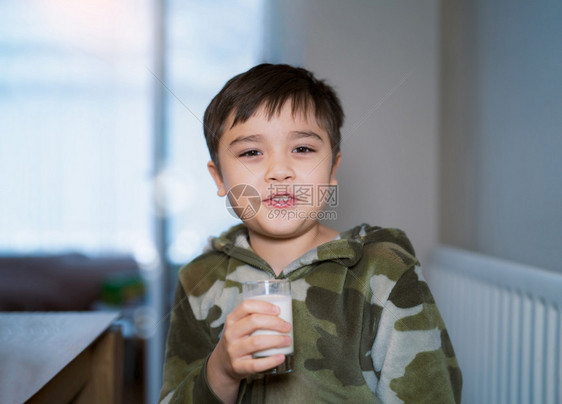 坐在桌边喝牛奶吃早饭的小男孩图片