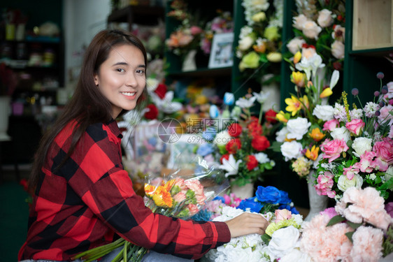 美丽的鲜花店老板和年轻家在里检查花卉的采活动者盆商业图片