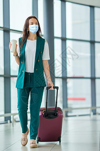 航空公司人们戴面罩防止在国际机场携带行李的旅游女客保护免受科罗纳和在国际机场携带行李的青年旅游女客在国际机场携带行李的女游客登机图片