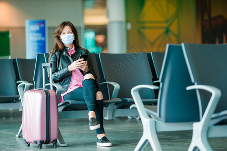 视窗运输戴面罩以防止在国际机场携带行李的在国际机场保护防止科罗纳和抓托克的妇女在国际机场携带行李的年轻女旅游客第6条经过图片