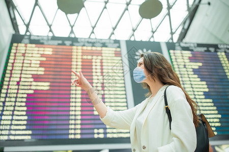 戴面罩以防止在国际机场携带行李的在国际机场保护防止科罗纳和抓托克的妇女在国际机场携带行李的年轻女旅游客第6条视窗大流行终端图片