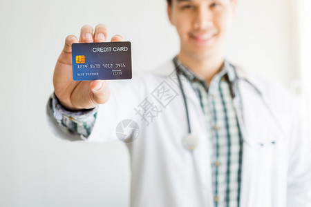 白种人亚洲年轻男子医生治疗咨询摘要与焦点模糊显示在房间医院背景的床上持有信用卡支付医疗费概念校对Portnoyunorg吸引人的图片