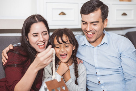 父亲和母以礼物或新的玩具给女儿惊喜父母和子女在家里沙发起居室时一快乐地生活在一起的家庭和生命幸福概念微笑孩子爱图片