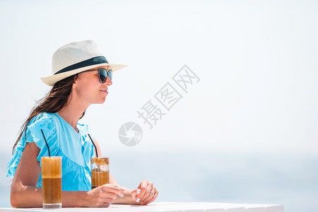 鸡尾酒成人年轻的女子喝着冷咖啡享受海景美丽的女士在海滩上外出度假期间放松在海滩上享受破烂的美食年轻女子喝着冷咖啡享受海景图片
