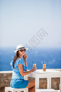 玻璃年轻女子喝着冷咖啡享受海景美丽的女士在海滩上外出度假期间放松在海滩上享受破烂的美食年轻女子喝着冷咖啡享受海景冰沙星乐图片