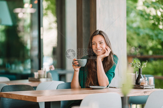 卡布奇诺美丽的女人在户外咖啡厅吃早餐放在手头美丽的女人在户外咖啡厅吃早餐快乐的年轻城市妇女喝着咖啡旅游美味的图片