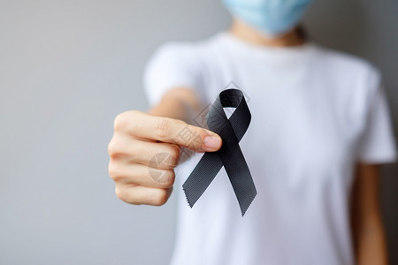 持有黑丝带用于梅兰诺马和皮肤癌疫苗伤害意识月悲与和平中休息的黑丝带妇女保健和种族主义概念丧年轻的世界图片