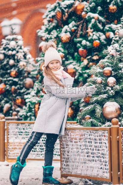 连指手套孩子冷杉圣诞市场的小美少女在新年的雪地中靠近小树枝处的快乐女孩儿新年图片