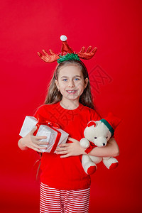 问候盒子一个有趣的快乐女孩肖像头上缠着角绷带抱一只泰迪熊穿着圣诞睡衣背景为鲜红色头抱着一只泰迪熊与鲜红色背景隔开拥抱图片