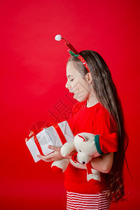 为了假期一种个有趣的快乐女孩肖像头上缠着角绷带抱一只泰迪熊穿着圣诞睡衣背景为鲜红色头抱着一只泰迪熊与鲜红色背景隔开图片