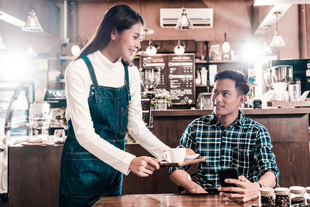 亚洲小企业主律师协会向咖啡店桌上的年轻顾客小商业主以及咖啡店和餐馆的创业者提供一杯咖啡小型商业主亚洲协会咖啡店和餐馆概念自助厅女图片