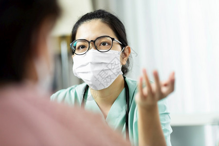新冠病物绿色制服亚洲女医生穿戴眼镜和外科口罩在医院症状疾病流感Covid19Corona医院向老年女患者提供咨询和从业者图片