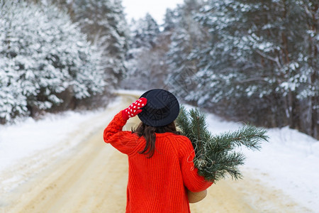 女一个穿着红色毛衣和帽子的女孩红色手套站在雪覆盖的道路中间在松枝的森林中周末旅行一个穿着红色毛衣和帽子的女孩红色手套站在雪覆盖的图片