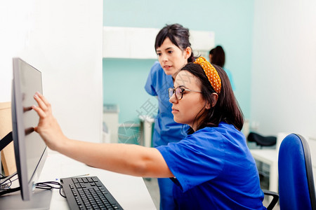 制服桌子两名护士在X光室使用计算机其中一名佩戴眼镜坐在书桌附近2名护士在X光室使用计算机2名护士在X光室使用计算机水平的图片