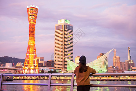夜晚地标假期在大阪附近的神户港旅行年轻女快乐亚洲旅行者在日落里程碑处看着美丽的现代建筑在日本兵库县神户市旅游景点很受青春欢迎图片