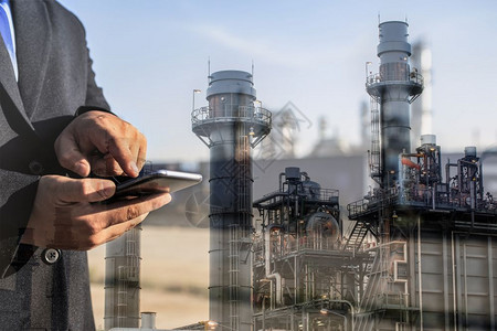 可再生工作站立商人在夜间用智能电话检查炼油厂工时双倍接触能源与技术概念的双重接触图片