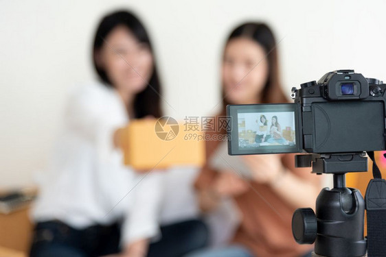 关闭数码视频摄像机记录两名女孩展示新产品广告Vlog和影响力人概念的新产品广告使用现代技术从事兼职工作和业的青年少利用现代技术从图片