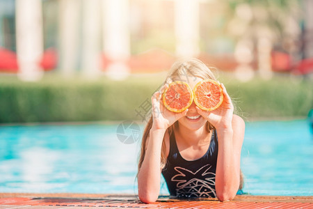 在泳池边拿着柚子的小女孩图片