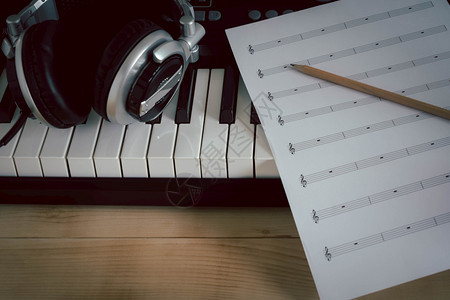 钢琴音乐器概念背景关闭音乐家制作歌曲的音乐工具组用纸笔和电子键盘棕色木制空间耳机以及纸上铅笔和电子键盘音乐会声图片