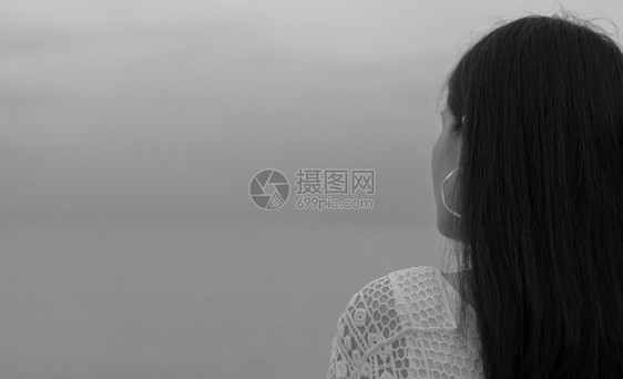 30多岁成人在海边的黑白场景中带着悲伤的心情回望着妇女沮丧和紧张的女孩站立看着灰色的天空和大海无望与绝思维图片