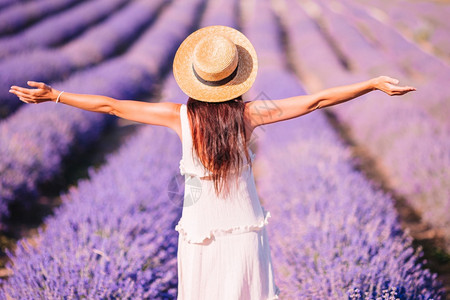 美丽的年轻女在紫花色衣草地上放松和玩得开心在白裙子和帽的日落时穿着紫花色朵田的女人们淑花的背景图片