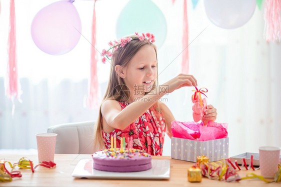 假期帽快乐的小女孩在她生日派对上解包希望概念Festive多彩背景与热气球留在家中Caucasian隔离区女孩充满梦幻般的笑容和图片