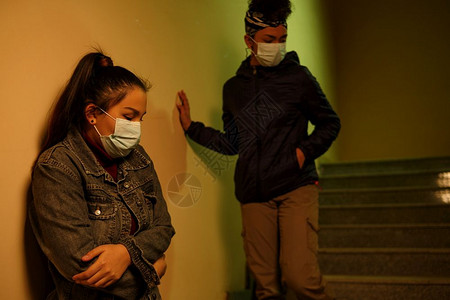 非洲人亚一名身着次医疗保护面罩的亚洲和非年轻女孩躲在楼梯井上避感染的人从感染中解救出跨种族的国际援助友谊和救a一名身着次医疗保护图片