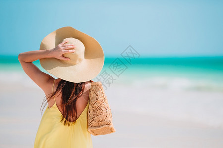 宁静天空在海滩上戴着帽子的漂亮女人背影年轻美丽的女士在热带海滨玩得开心快乐女孩的背景是蓝天和西里伯恩岛海水中的绿石闲暇图片