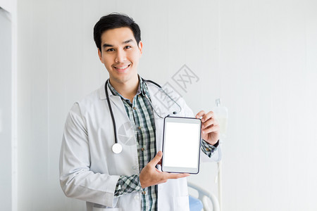 药片成人空白的亚洲青年男子医生治疗咨询带有积极情绪的治疗建议用空白屏幕显示数字平板片在医院背景复本空间中铺床和位图片