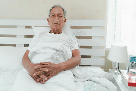 躺在医院病床上并带着鼻喉呼吸管的老人图片