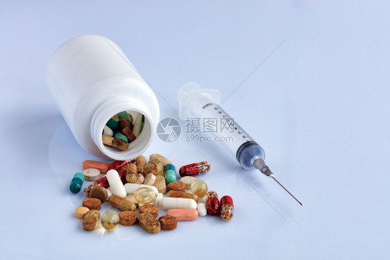 补充片剂和胶囊从一次注射器附近的白色光滑桌子上的白色瓶中散落出来止痛药物图片