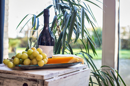 靠近窗户的桌子上放着葡萄和酒的奶酪拼盘配有舒适的椅子现代室内设计豪华装饰食物和室内概念美味的奶酪拼盘靠近窗户的桌子上放着葡萄和酒图片