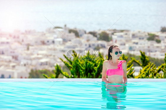 轮廓假期年轻美女享受豪华安静的游泳池年轻美女在室外豪华游泳池享受暑假日光浴图片