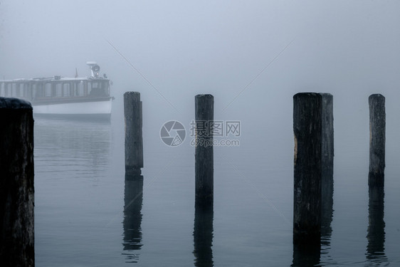 宁静反射德国科尼格西湖的雾中木头码和单船与在雾中失落的木桩上瓶子谷图片