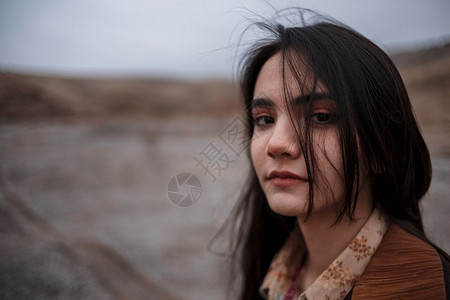 在山岳背景下暴风雨中一位年轻黑发女孩的戏剧肖像肉欲情感黑暗的图片