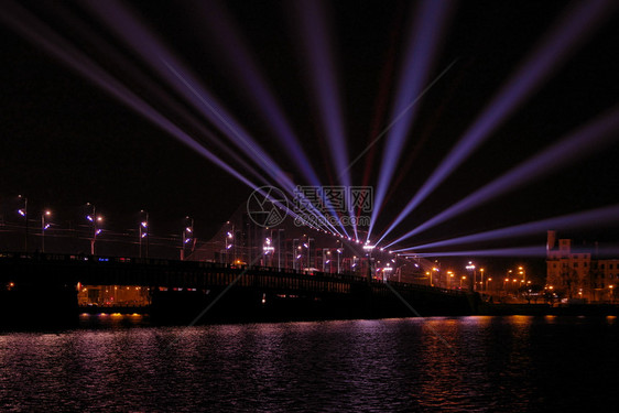 Akmens桥横渡道加瓦河的蓝色亮光从对面投射的蓝光点束图像黄昏灯城市图片