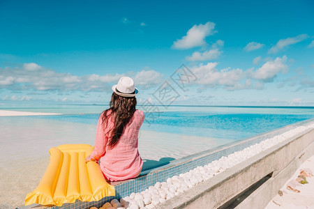 天堂马尔代夫美丽的年轻女孩在户外游泳池里放松美丽的年轻女子在游泳池里放松在豪华酒店的室外游泳池里快乐的女孩日光浴图片