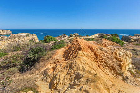 植被自然葡萄牙海岸的橙状岩石山脉和绿植树支撑图片