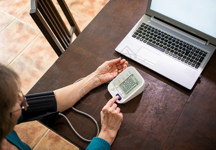 现代的远程医疗概念老年妇女在她厨房带血压的视频电话网上咨询中进行在线居住关心图片