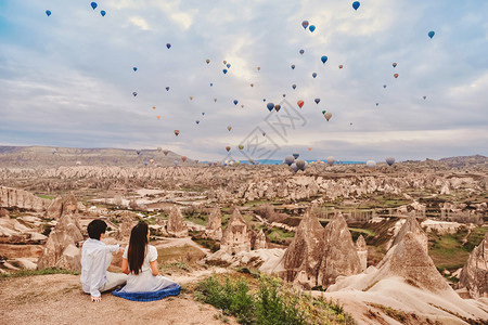 亚洲情侣看着多彩的热气球在土耳其卡帕多西亚山谷上飞过爱的浪漫时光地标爬坡道运输图片