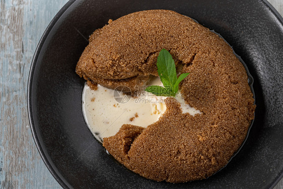 土耳其以黑陶瓷板上的冰淇淋在木制反面石蜡上配有Halva冰淇淋的SemolinehalvaHalva冰淇淋甜的陶瓷制品图片