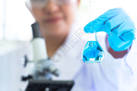 样本女科学家持有并展示实验室测试管和溶液具有听诊镜科学和医背景与科家研究和分析生物技术概念重点突出的蓝色玻璃瓶精选焦点突出的蓝玻图片