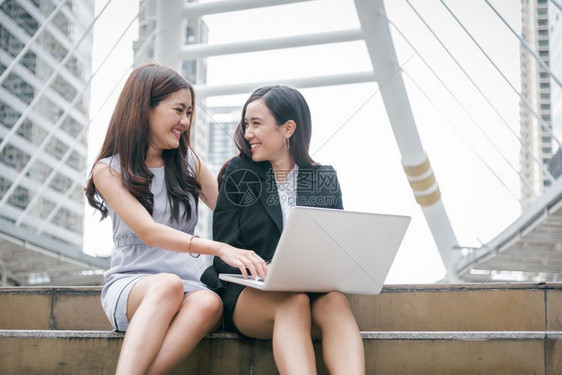 商界女专业的社会两名从事膝上型计算机工作的女商人她们拥有快乐的趣情感激动式笔记本电脑商业办公室雇员技术协作企业工团队合作会议营销图片