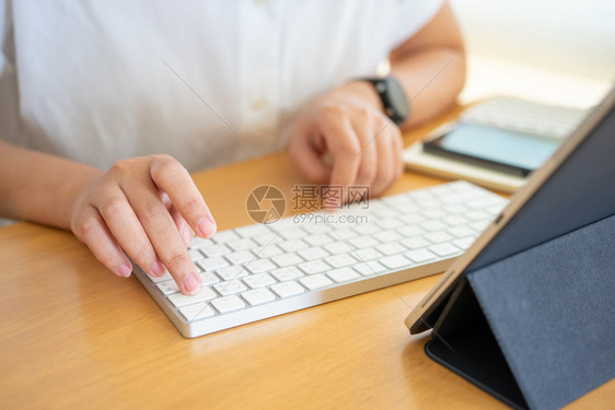 笔记本电脑在家庭办公室工作并打键盘智能手机平板在线工作或学习同时使用智能手机平板自由工作商业概念的打字年轻自由职业者或商界人士敲图片