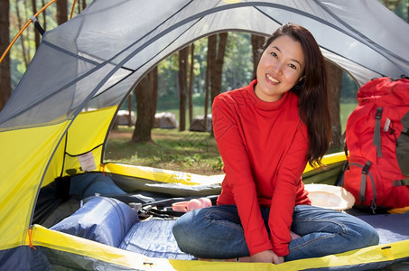 一位身穿红色衬衫露营的美女坐在黄色帐篷里背着红色包女松弛幸福图片