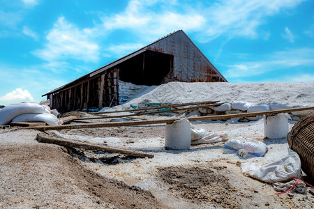 袋式有机海盐和竹篮在谷仓前的笼子里用蓝天和夏月白云蓝天和做成沙质工业用盐水袋中的海洋原料碘治疗农场图片