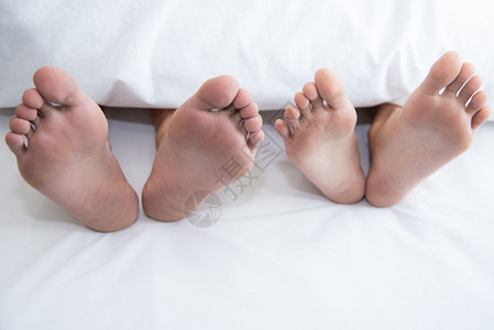 幸福说谎在蜜月度假期的卧室里赤脚裸在毯子下紧贴一对夫妇在蜜月假日的卧房里周末很长时间在家里婚礼仪式后与浪漫人士放松爱图片