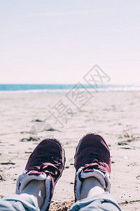 年轻女子在运动鞋和牛仔裤中的脚足在沙滩上徒步旅行后轻松放POV冒险概念背景激励引文博客章你的本Toned图像阳光平静的鞋类图片