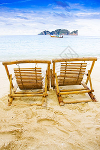 座位风景优美海滨两位木林教席坐在泰国热带岛屿海滩上与远洋长船一起坐落在泰国热带岛屿海滩的一个位置照片ThotophLangPhi图片
