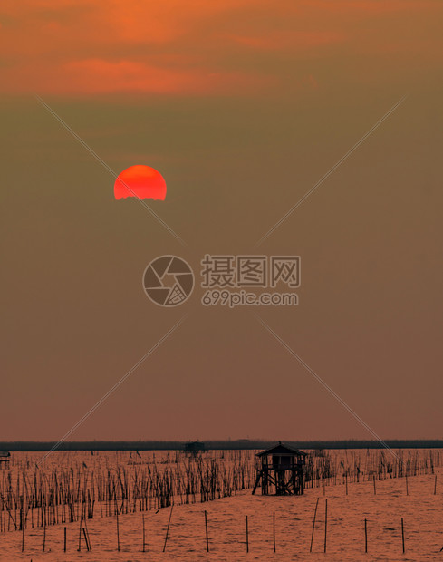 黄昏时海面上美丽的夕阳天空光被日落时的乌云遮蔽在泰国海岸钓鱼的渔夫小屋黄昏时席丽休埃特海景和沿小屋轮廓洋日出图片